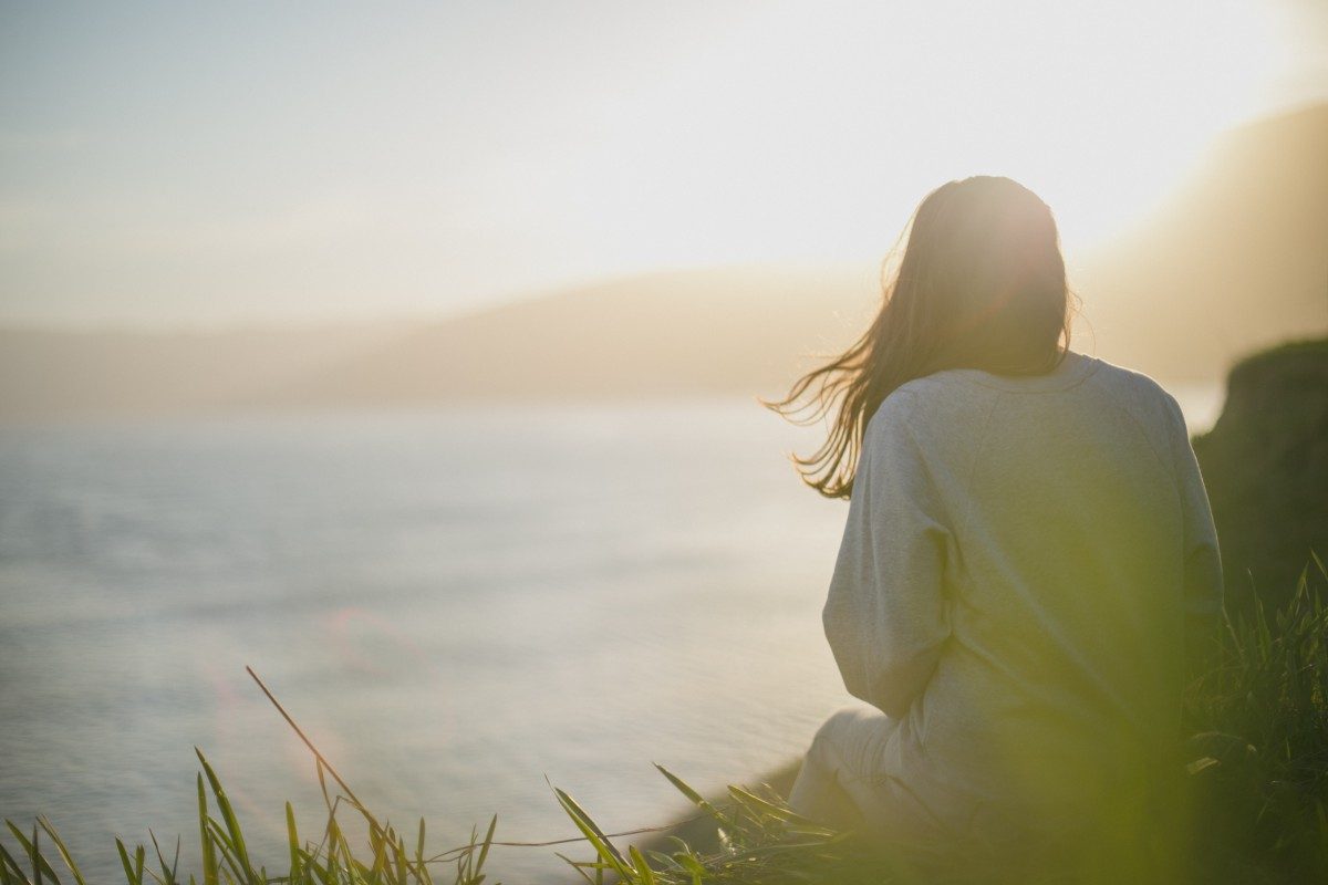 Woman sitting calmly by the sea at sunset